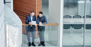 Two businessmen in a modern office building discuss documents. Professional and collaborative environment.